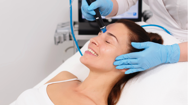 Woman receiving hydrafacial treatment from a cosmetologist in a professional beauty clinic